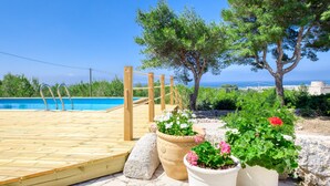 A wooden deck leading to a pool with potted plants and trees in the background. - Sea view pool villa w/ garden, 2km from sand (Torre Pali)