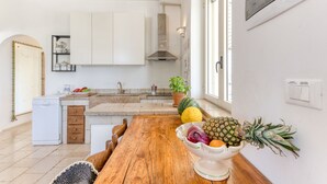 A kitchen with white cabinets, a wooden table, and a bowl of fruit. - Sea view pool villa w/ garden, 2km from sand (Torre Pali)
