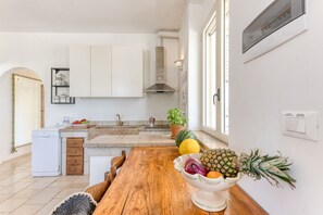 A kitchen with white cabinets, a wooden table, and a bowl of fruit. - Sea view pool villa w/ garden, 2km from sand (Torre Pali)