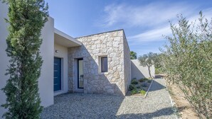 Un bâtiment moderne avec une façade en pierre, une porte bleue et une allée gravillonnée.