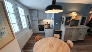 A modern kitchen with white cabinets, a central island, and a round wooden table with chairs.