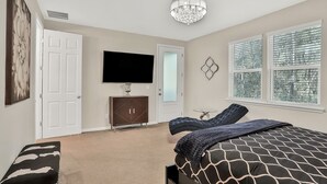 A bedroom with a bed, a TV, a dresser, and a window with blinds. - COZY 4 BEDROOM RANCH NEAR JAX (Jacksonville)