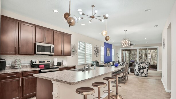 A modern kitchen with dark wooden cabinets, stainless steel appliances, and a large island with bar stools. - COZY 4 BEDROOM RANCH NEAR JAX (Jacksonville)