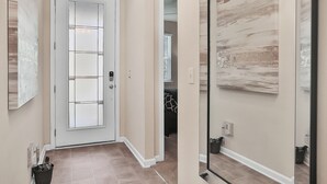 A hallway with a frosted glass door, beige walls, and a tiled floor. - COZY 4 BEDROOM RANCH NEAR JAX (Jacksonville)