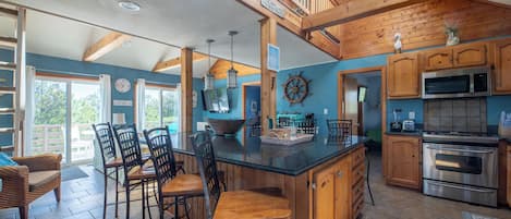 Una cocina amplia con armarios de madera, una isla grande y una zona de comedor con sillas.