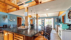 A spacious kitchen with a large island, wooden cabinets, and nautical-themed decor. - The Swan Shack - 4x4 Carova Beach, Pool, Hot Tub, Theater, Pets OK, Private Setting (Carova Beach)