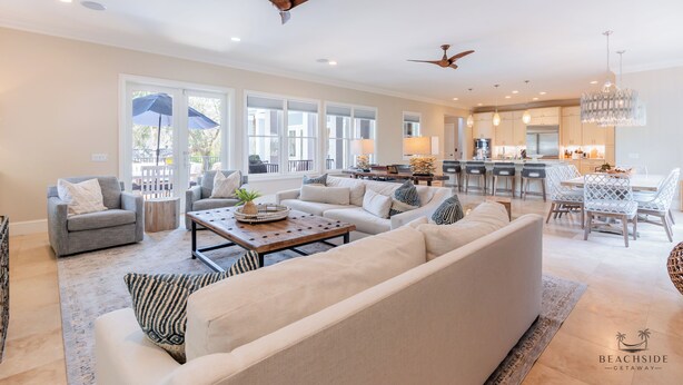 A spacious living room with a large sofa, a coffee table, and a dining area with a chandelier.