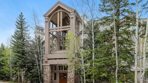 Un immeuble à plusieurs étages, doté d’une façade en pierre et de grandes fenêtres, entouré d’arbres.