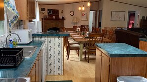 A kitchen with wooden cabinets, a sink, a stove, and a dining area with chairs and a table. -  Trail Side Inn 4 bed 2 bath with trail access to 4 Hatfield-McCOY trails system (northfork)
