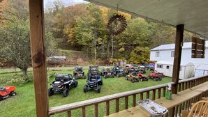 A covered porch with a view of a grassy area with various ATVs parked. -  Trail Side Inn 4 bed 2 bath with trail access to 4 Hatfield-McCOY trails system (northfork)