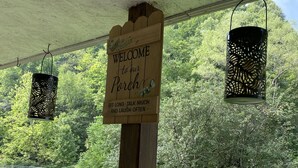 A wooden sign with a welcome message and a lantern hanging from a structure. -  Trail Side Inn 4 bed 2 bath with trail access to 4 Hatfield-McCOY trails system (northfork)