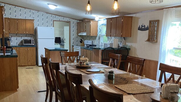 A spacious kitchen with wooden cabinets, a dining table with chairs, and pendant lighting. -  Trail Side Inn 4 bed 2 bath with trail access to 4 Hatfield-McCOY trails system (northfork)