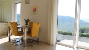 A dining area with a table and chairs, a vase with flowers, and a painting on the wall.