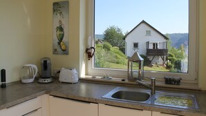 A kitchen with a large window, a coffee maker, a toaster, and a sink.
