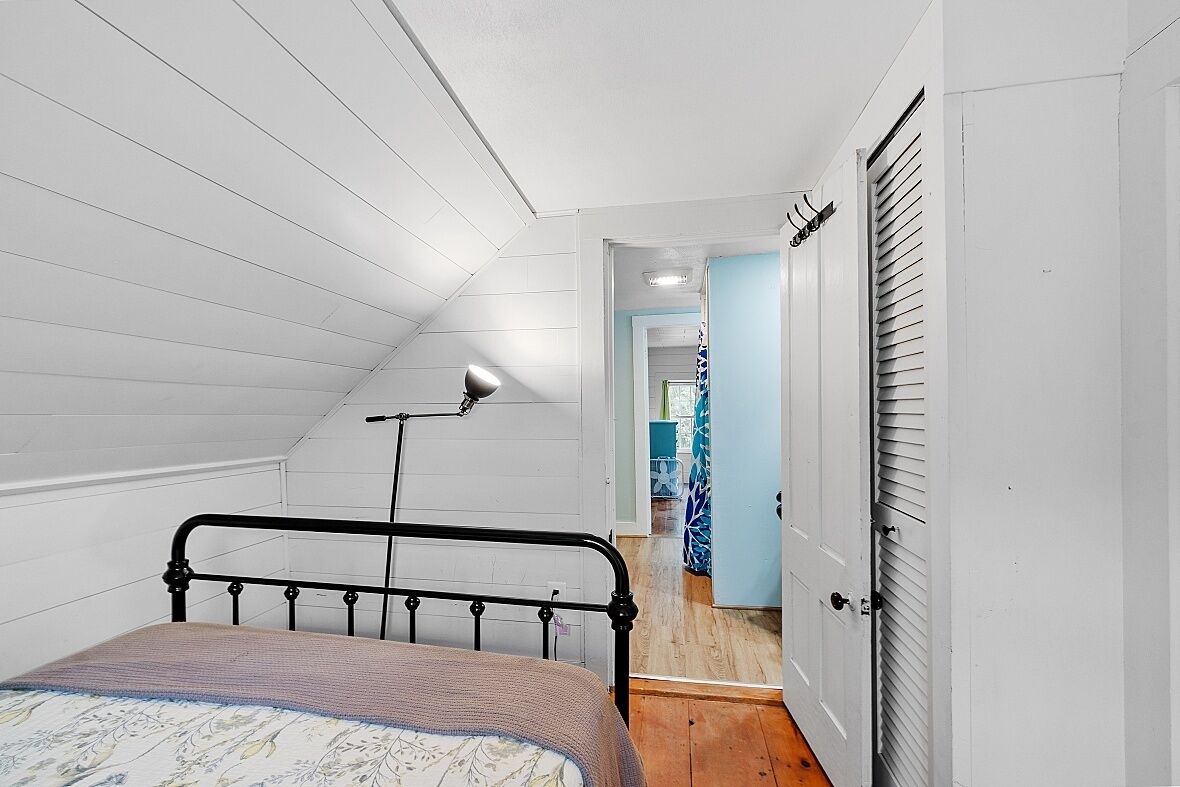 A bedroom with a bed, a ceiling fan, and a door leading to another room.