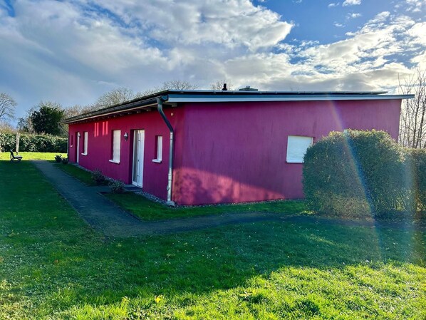 Simple, single-story building with a flat roof and pathway leading to the entrance.