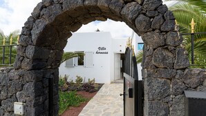 A stone archway leading to a building labeled "Villa Hermosa" with a paved pathway and a small garden area. - Private villa with pool and whirlpool in a quiet location (Puerto del Carmen)