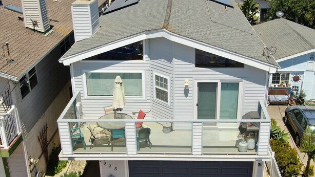 Una casa a due piani con un balcone, un garage e pannelli solari sul tetto.