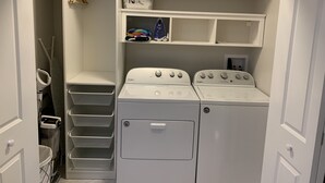 Ein Waschraum mit zwei Whirlpool-Waschmaschinen, einem Wäscheständer und beschrifteten Aufbewahrungsbehältern für 'Twin' und 'Twin'.