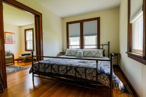 Une chambre à coucher avec un lit, un plancher en bois et une fenêtre avec des stores.