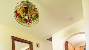 A dining area with a wooden table, chairs, a patterned rug, and a stained glass chandelier. - Residence on the Roundabout (St Charles)