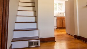 A wooden staircase leading to a kitchen area with a window above the sink. - Residence on the Roundabout (St Charles)