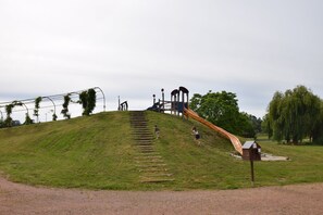 Une aire de jeux avec un toboggan, des éléments d’escalade et une structure en bois.