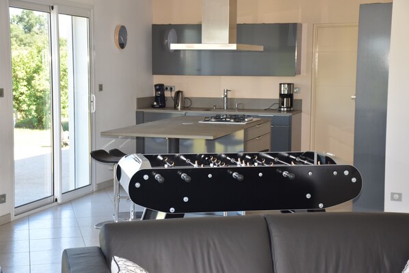 A modern kitchen with a gas stove, coffee maker, and a view of the outdoors through a sliding glass door.