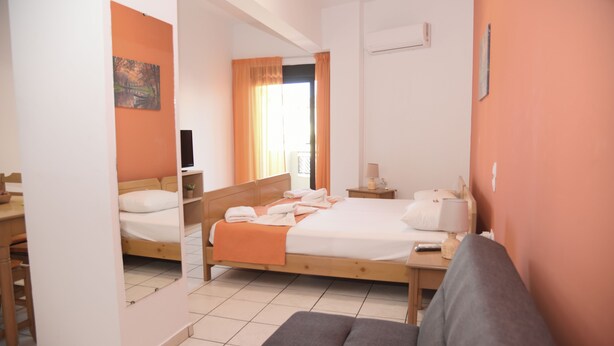 A hotel room with two beds, a sofa, a desk, and a window with curtains. - Economic Studios  B3 (HERAKLION CRETE)