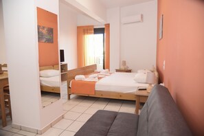 Ein Hotelzimmer mit zwei Betten, einem Schlafsofa, einem Schreibtisch und einem Fenster mit Vorhängen.