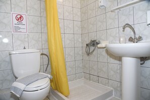 Ein Badezimmer mit Toilette, einer Dusche mit gelbem Vorhang und einem Waschbecken.