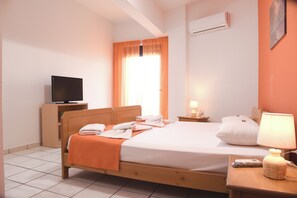 Ein Hotelzimmer mit Bett, Fernseher, Nachttisch, Lampe und Klimaanlage.