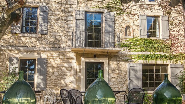 A stone building with multiple windows, a balcony, and outdoor seating. - Full of character, standing, SWIMMING POOL, large GARDEN, QUIET CHARM & BEAUTY (Avignon)