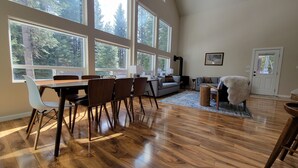A spacious living room with a large dining table, multiple chairs, a sofa, and a fireplace. - Luxe family and pet friendly chalet in private, forested setting (Leavenworth)