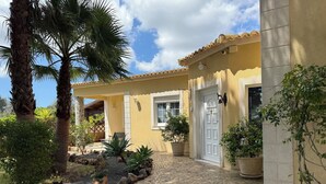 A house with a tiled patio, a white door, and potted plants. - Villa V5 Piscine et Spa (São Bartolomeu de Messines)