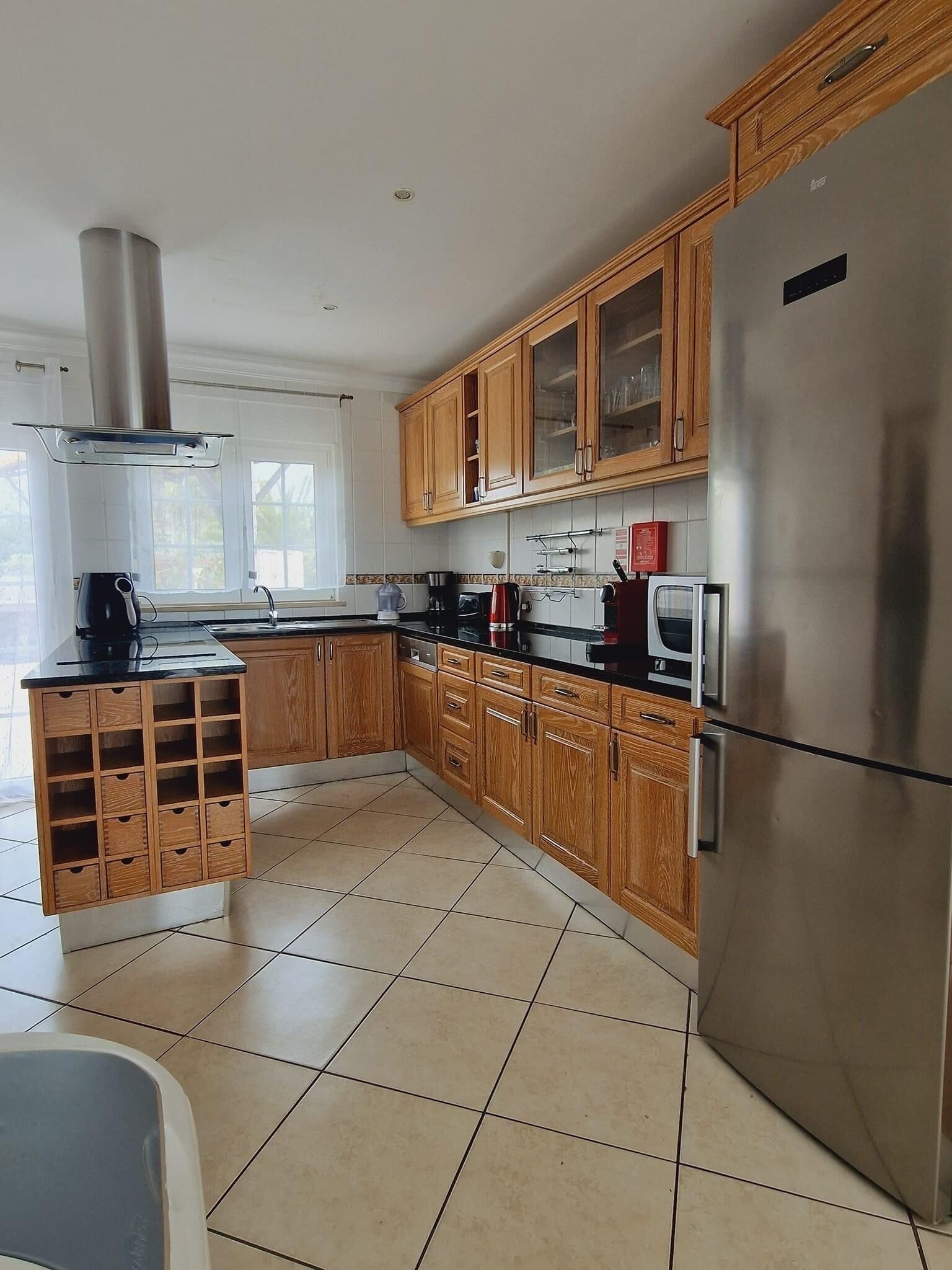 Una cucina moderna con mobili in legno, frigorifero in acciaio inossidabile e piano cottura a gas.