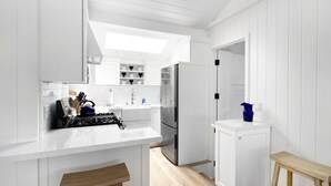 Eine moderne Küche mit weißen Schränken, einem Edelstahlkühlschrank und einem Oberlicht über der Spüle.