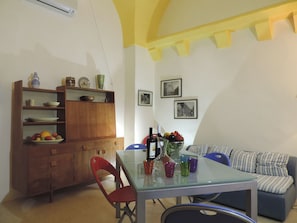 A dining area with a glass table, chairs, a wooden cabinet with dishes, and a sofa. - Villa Palazzo del Diavolo:Il Patio e le Terrazze,WiFi,AC,TouristPersonalAdvisor (Parabita)