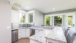 Cozinha moderna com armários brancos, bancadas de granito e lava-louças embutida.