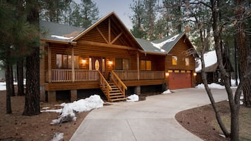 Une cabane en rondins avec une façade en bois, un porche à l’avant et un escalier menant à l’entrée.