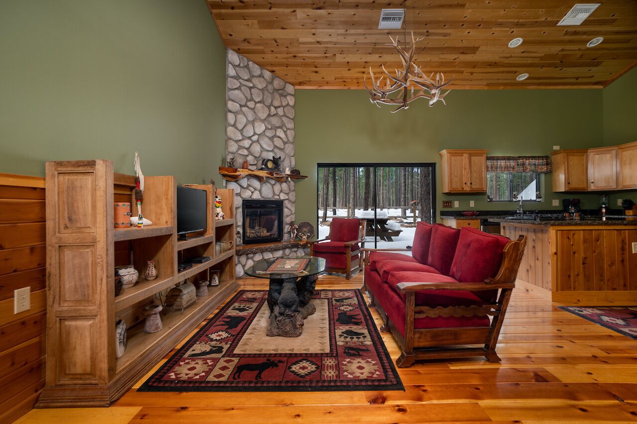Un salon chaleureux avec une cheminée en pierre, des meubles en bois et un canapé rouge.