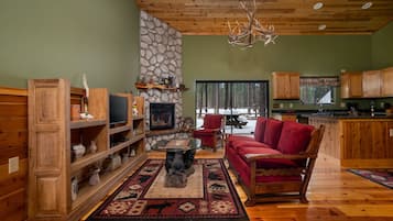 Un salon chaleureux avec une cheminée en pierre, des meubles en bois et un canapé rouge.