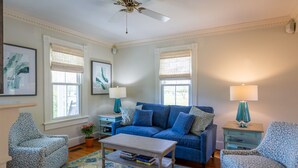 A living room with a blue sofa, patterned armchairs, a coffee table, and a ceiling fan. - Irvington Country Getaway House (Irvington)