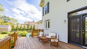 A wooden deck with outdoor furniture, a sliding glass door, and a white house with a picket fence. - Irvington Country Getaway House (Irvington)