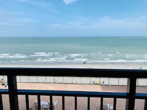 A beach view from a balcony with a railing, a sandy beach, and the ocean. - Breathtaking Views & Bliss in our Oceanfront Suite (Myrtle Beach)