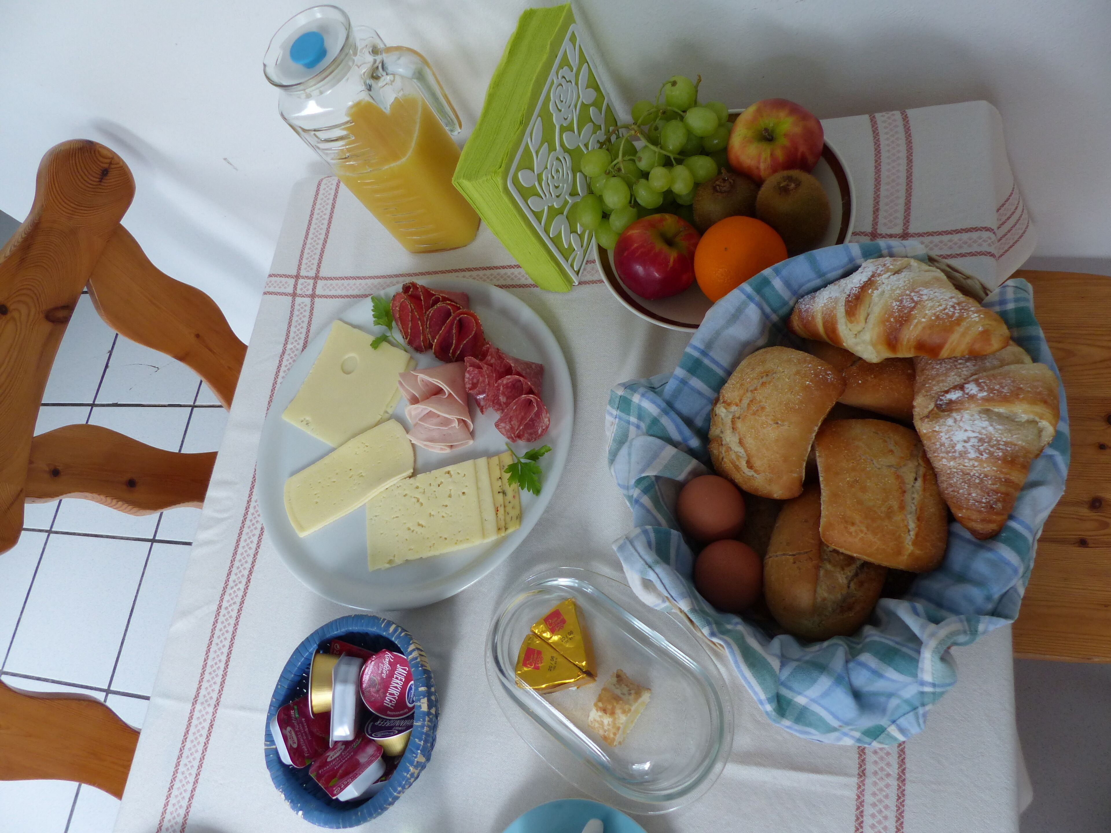 A table with various food items including cheese, meats, fruits, and bread.