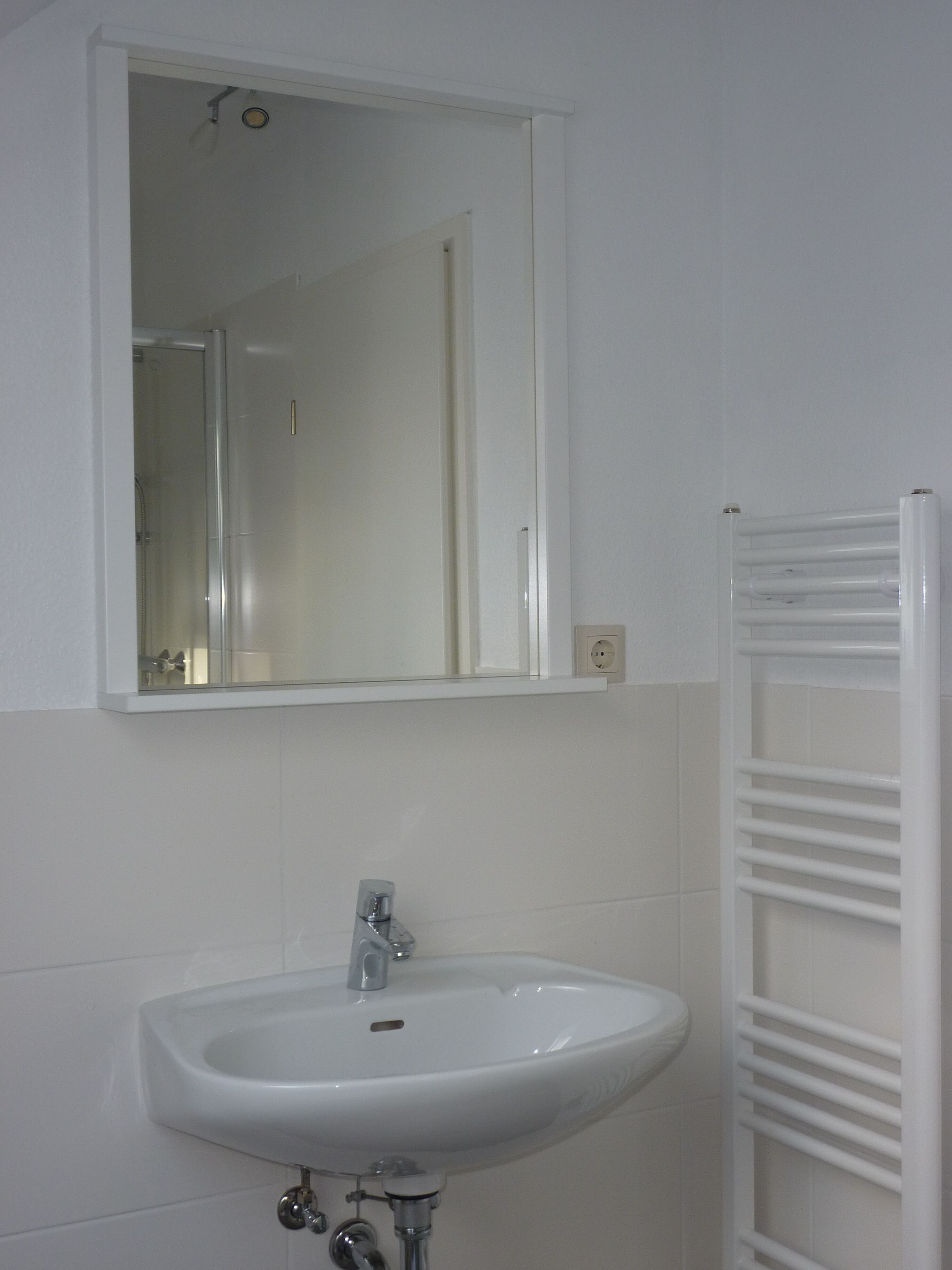A bathroom with a white sink, a mirror, and a white towel rack.