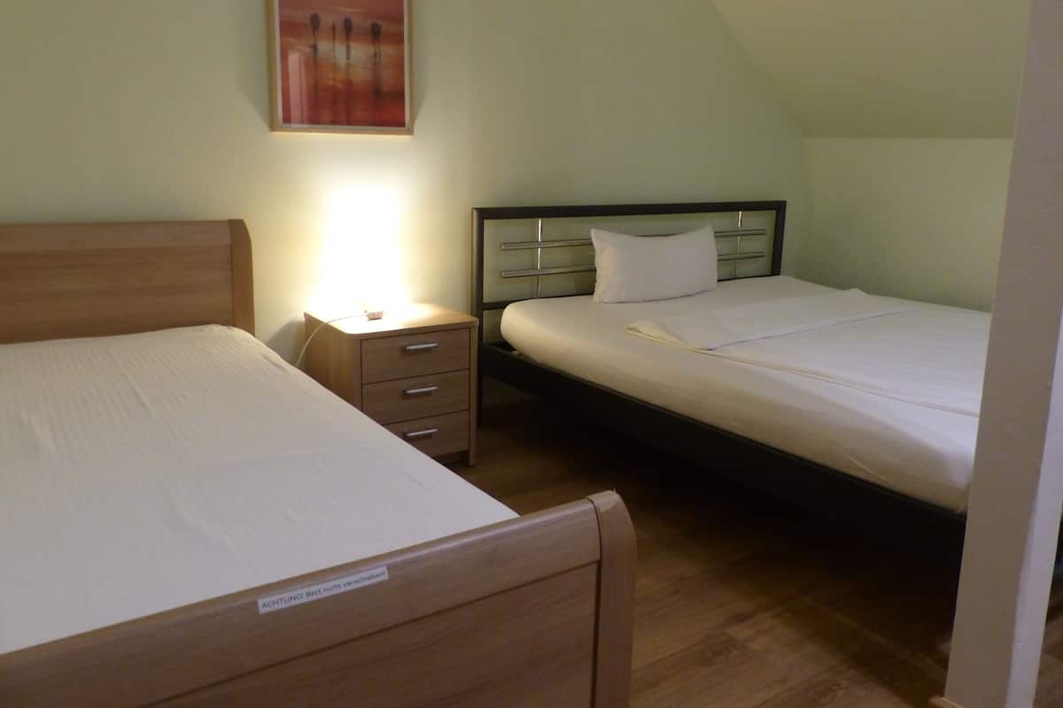 Ein Schlafzimmer mit zwei Betten, einem Nachttisch und einer Wandlampe.