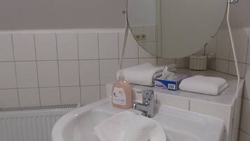 Un baño con un lavamanos blanco, un espejo y un perchero para toallas.