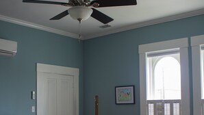 A bedroom with a bed, a ceiling fan, a window with shutters, a small table, and a chair. - Artistic Lodging Queen suite (Paris)
